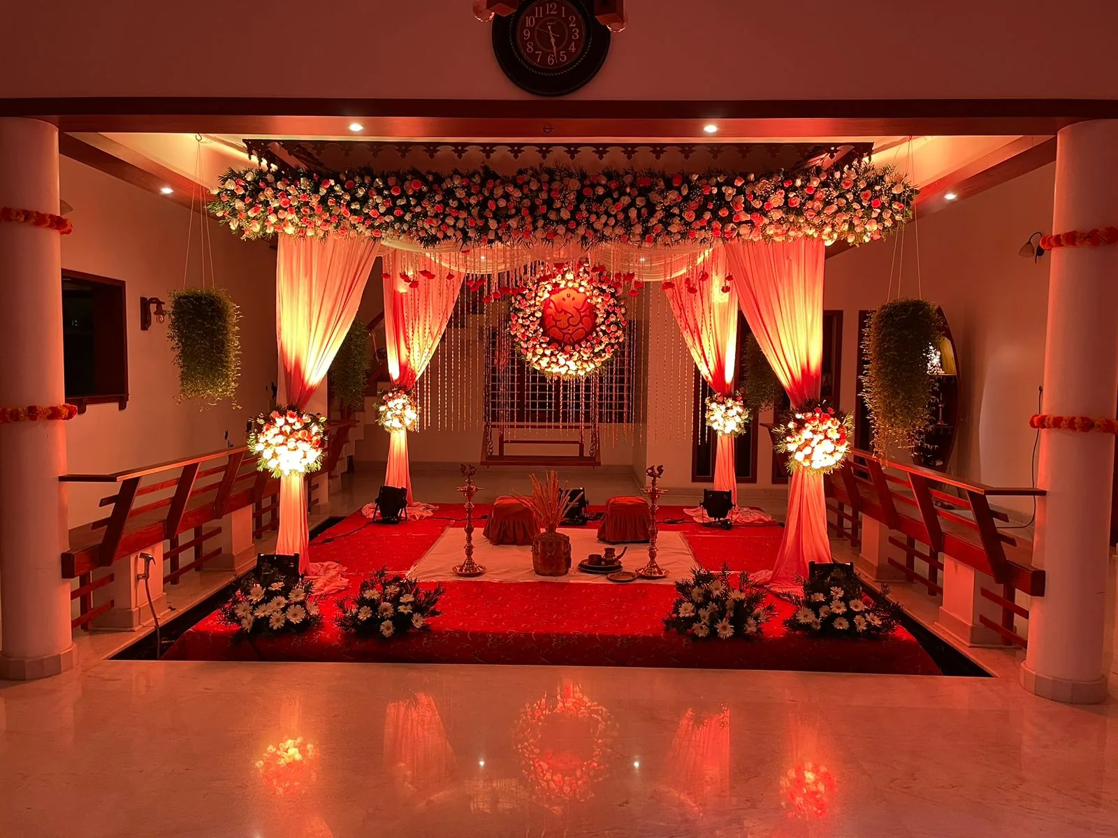 Wedding mandap with draped pillars, roses and brass lamps